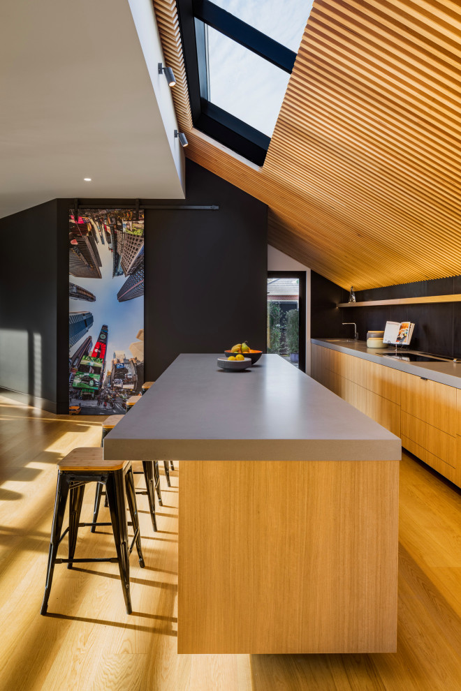 Large contemporary galley open plan kitchen in Melbourne with solid surface benchtops, with island, brown floor, grey benchtop, flat-panel cabinets, medium wood cabinets and medium hardwood floors.