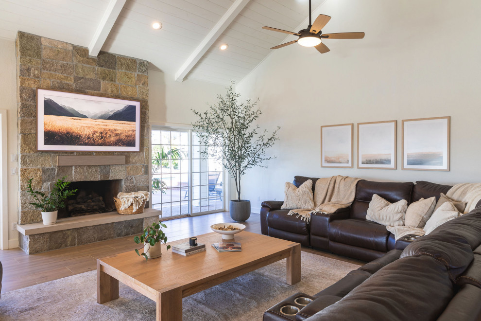 Large transitional open concept living room in San Diego with white walls, ceramic floors, a stone fireplace surround, brown floor, vaulted, exposed beam, timber and a standard fireplace.
