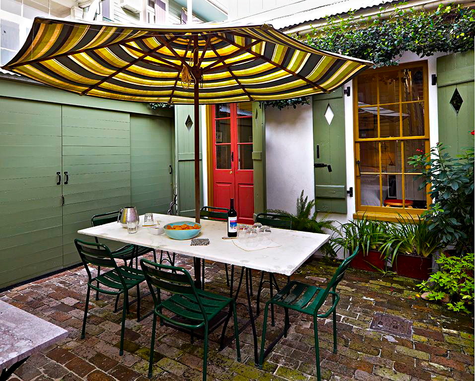 This is an example of an eclectic courtyard patio in New Orleans with brick pavers and an awning.