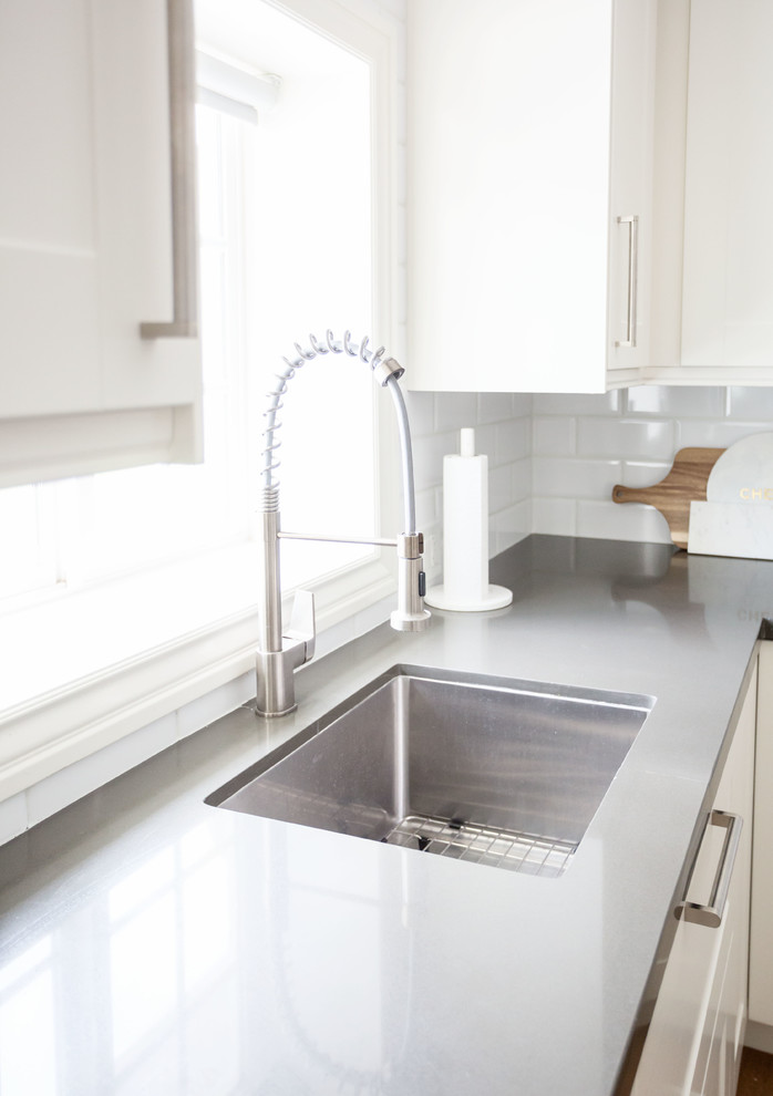 Large transitional u-shaped light wood floor and brown floor eat-in kitchen photo in Phoenix with a farmhouse sink, recessed-panel cabinets, white cabinets, quartz countertops, white backsplash, subway tile backsplash, stainless steel appliances, an island and white countertops