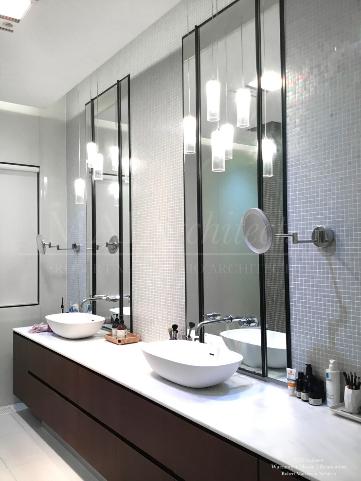 Photo of a large contemporary master bathroom in Melbourne with recessed-panel cabinets, white cabinets, a claw-foot tub, an open shower, a wall-mount toilet, multi-coloured tile, mosaic tile, a vessel sink, marble benchtops, an open shower and white benchtops.