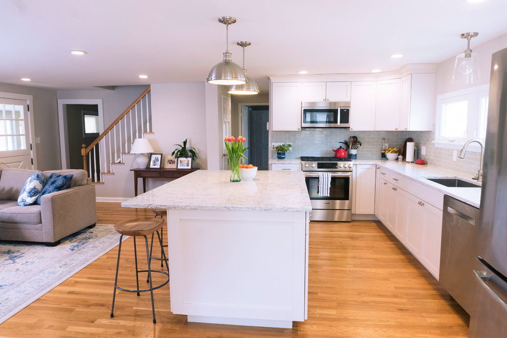 Photo of a mid-sized traditional l-shaped eat-in kitchen in Boston with a double-bowl sink, flat-panel cabinets, white cabinets, quartzite benchtops, blue splashback, subway tile splashback, stainless steel appliances, dark hardwood floors, with island, brown floor and grey benchtop.