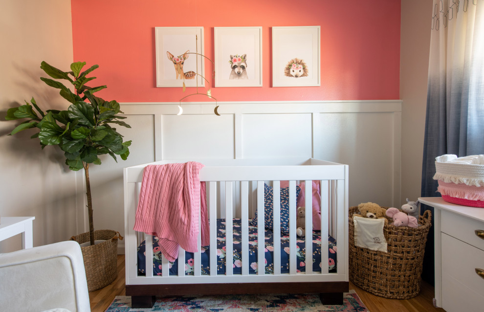 Inspiration for a small eclectic nursery for girls in Denver with pink walls, light hardwood flooring and wainscoting.