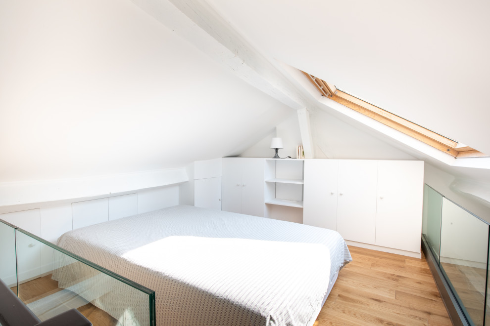 Imagen de dormitorio tipo loft y blanco y madera actual con paredes blancas, suelo de madera clara y vigas vistas