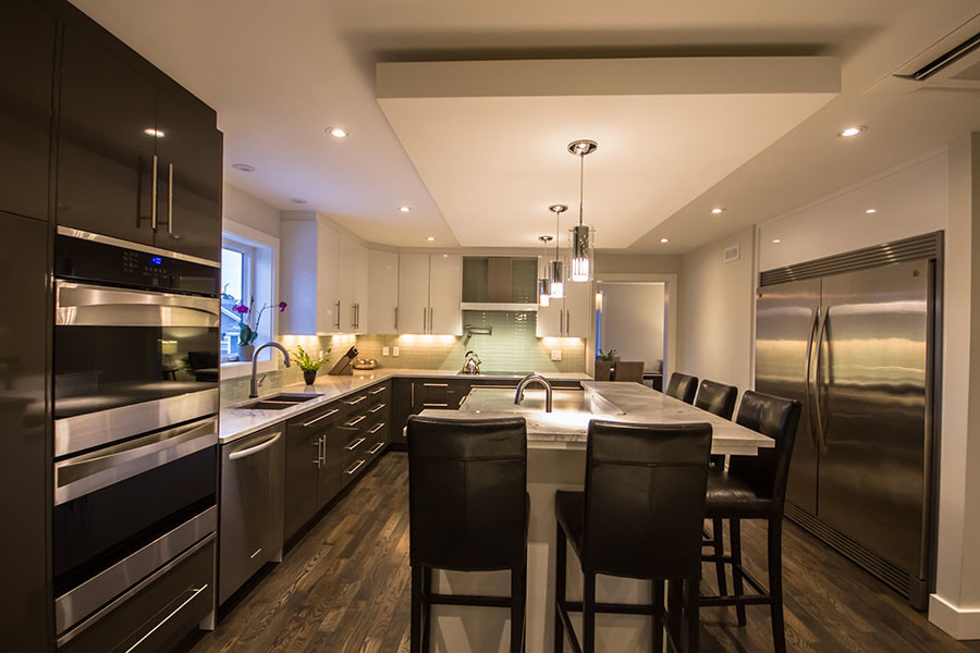 Example of a large transitional l-shaped dark wood floor open concept kitchen design with an undermount sink, flat-panel cabinets, white cabinets, granite countertops, green backsplash, glass tile backsplash, stainless steel appliances and an island