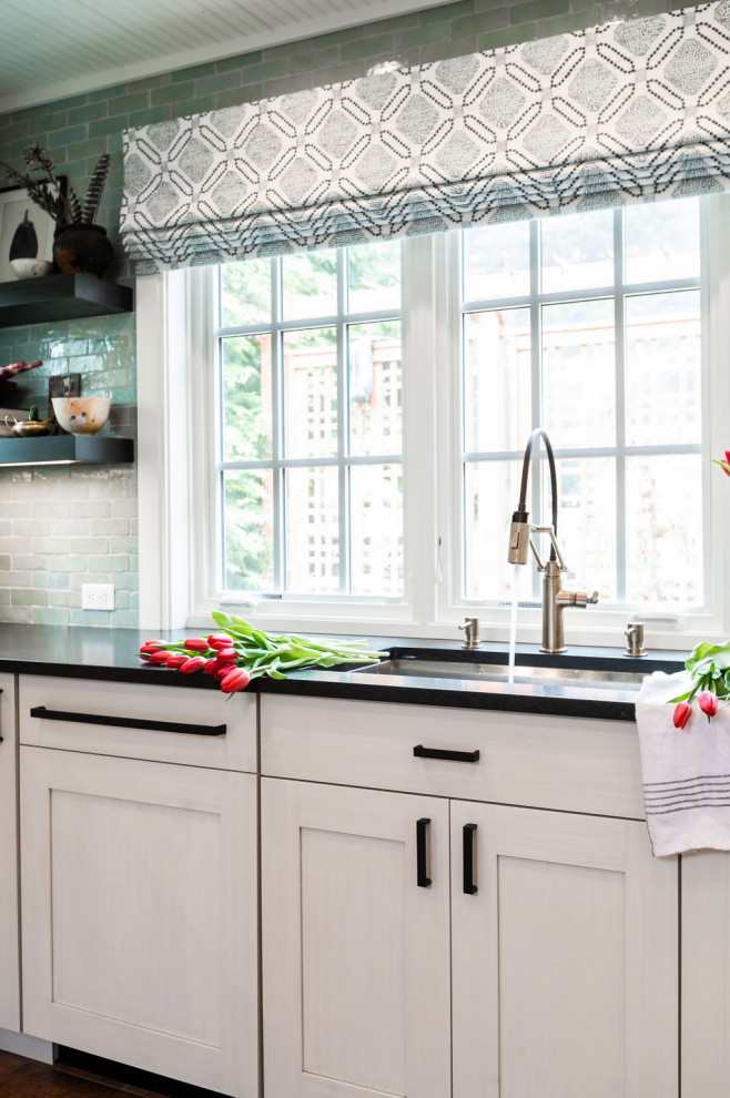 Immagine di una cucina abitabile chic con lavello sottopiano, ante bianche, elettrodomestici in acciaio inossidabile, top nero, paraspruzzi con piastrelle in terracotta e top in granito