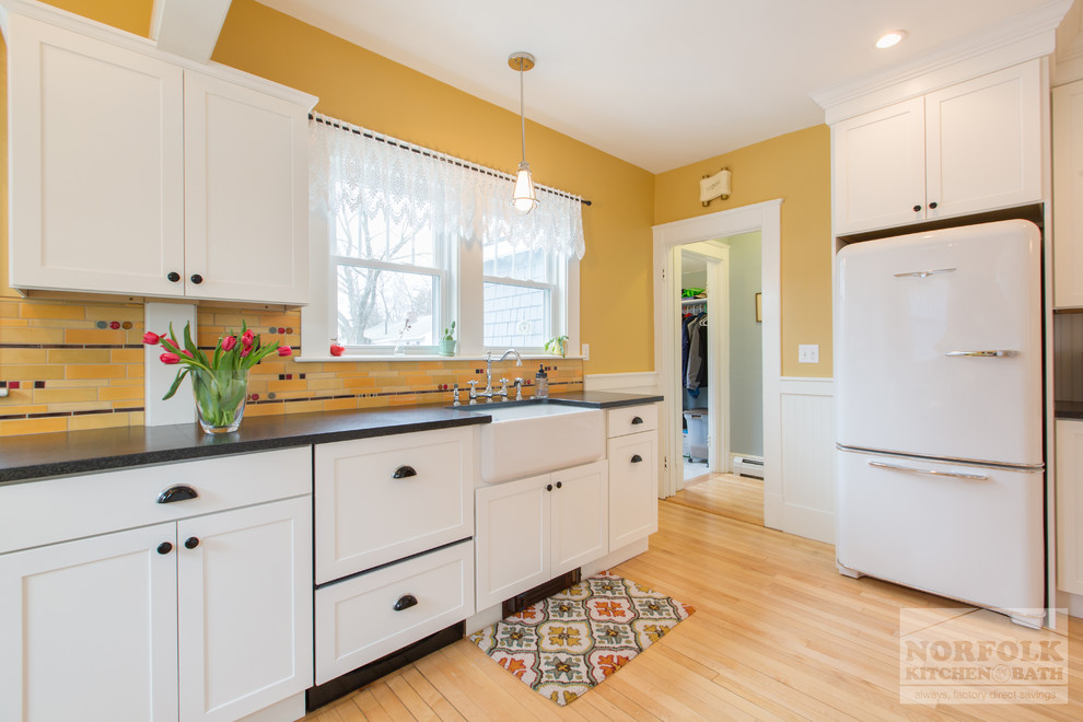Photo of a mid-sized arts and crafts eat-in kitchen in Boston with a single-bowl sink, white cabinets, granite benchtops, multi-coloured splashback, white appliances, light hardwood floors and no island.