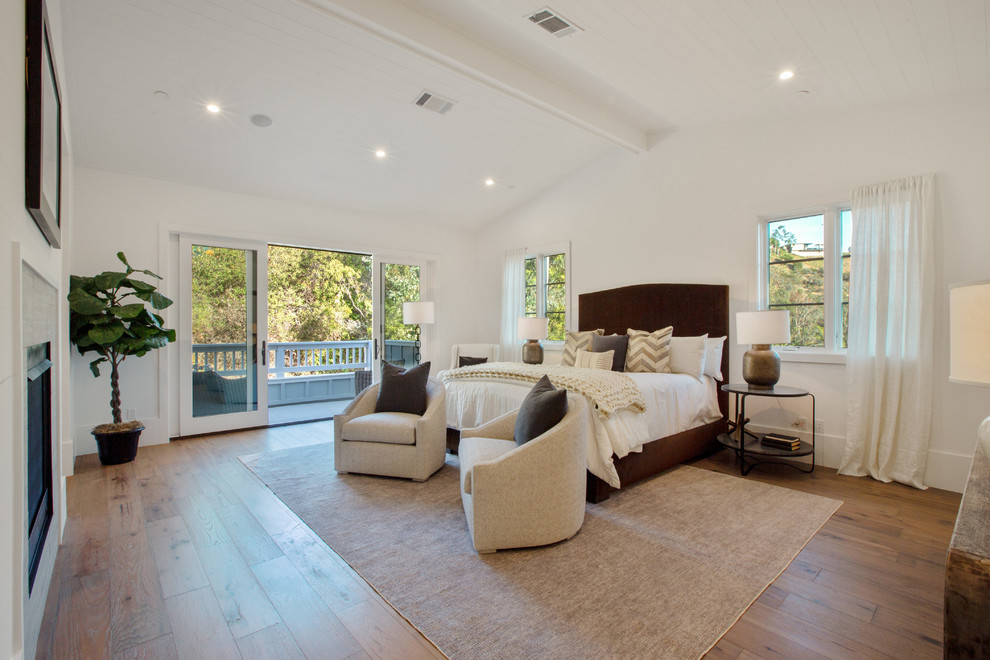Design ideas for a transitional bedroom in Los Angeles with white walls, medium hardwood floors, a standard fireplace and brown floor.