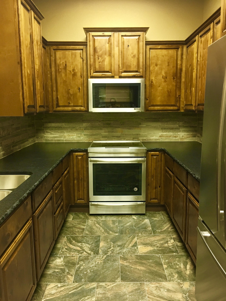 Mid-sized transitional l-shaped porcelain tile enclosed kitchen photo in Austin with a double-bowl sink, raised-panel cabinets, dark wood cabinets, granite countertops, beige backsplash, stone tile backsplash, stainless steel appliances and no island