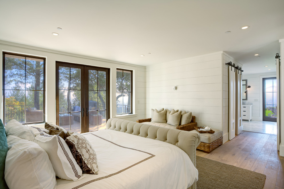 This is an example of a mid-sized country master bedroom in San Francisco with white walls, light hardwood floors and no fireplace.