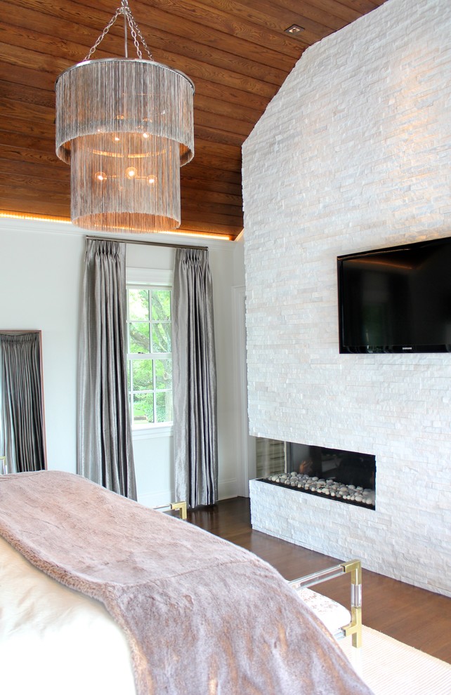 This is an example of a large contemporary master bedroom in Los Angeles with white walls, dark hardwood floors, a ribbon fireplace and a brick fireplace surround.