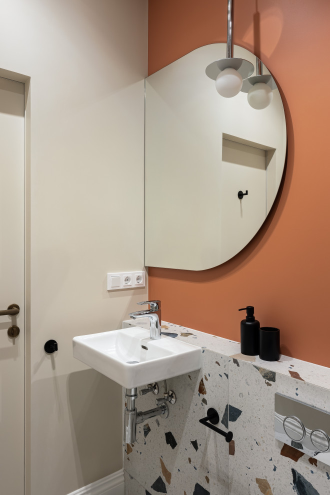 Идея дизайна: туалет среднего размера в стиле неоклассика (современная классика) с инсталляцией, зеленой плиткой, керамогранитной плиткой, оранжевыми стенами, полом из керамогранита, подвесной раковиной и разноцветным полом