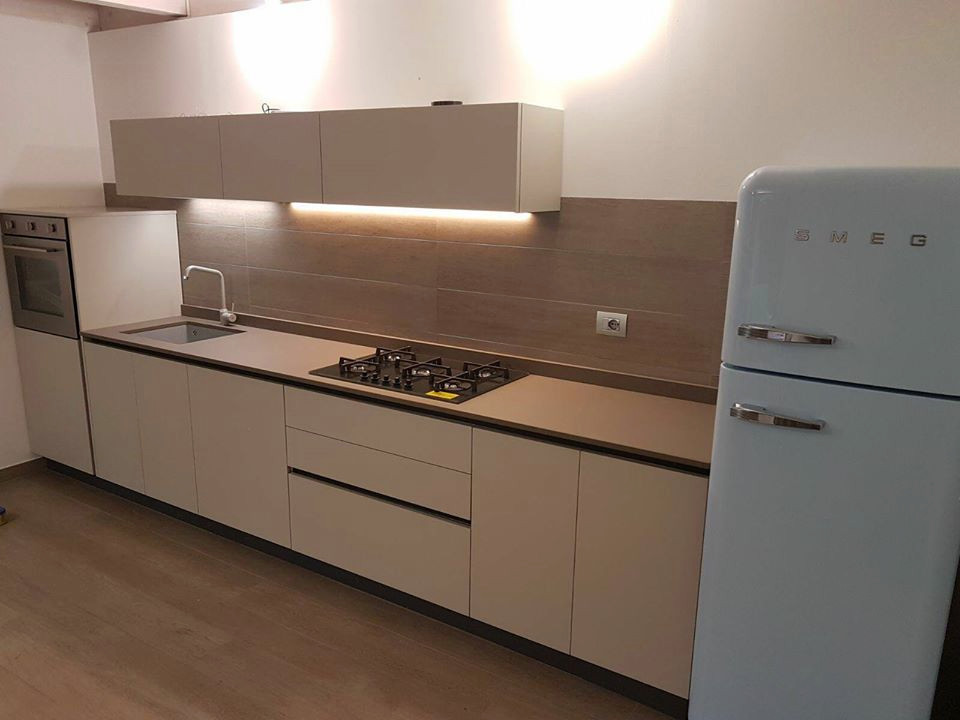 Small modern single-wall open plan kitchen in Milan with flat-panel cabinets and beige cabinets.