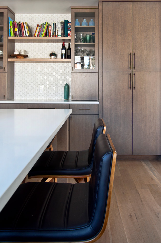 This is an example of a mid-sized midcentury l-shaped separate kitchen in Nashville with an undermount sink, flat-panel cabinets, medium wood cabinets, quartz benchtops, white splashback, marble splashback, black appliances, light hardwood floors, with island, brown floor and white benchtop.