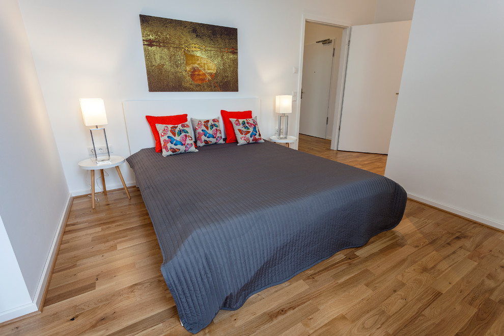 Mittelgroßes Retro Hauptschlafzimmer ohne Kamin mit weißer Wandfarbe, braunem Holzboden und braunem Boden in Leipzig