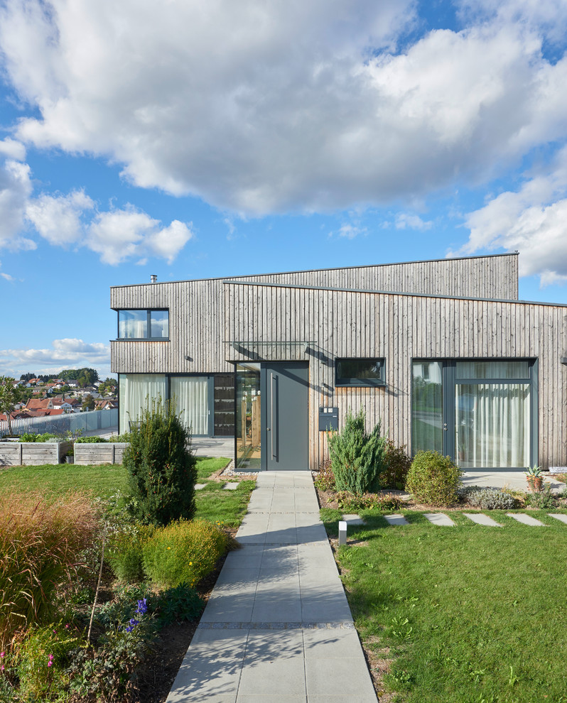 Design ideas for a contemporary grey house exterior in Stuttgart with wood siding and a shed roof.