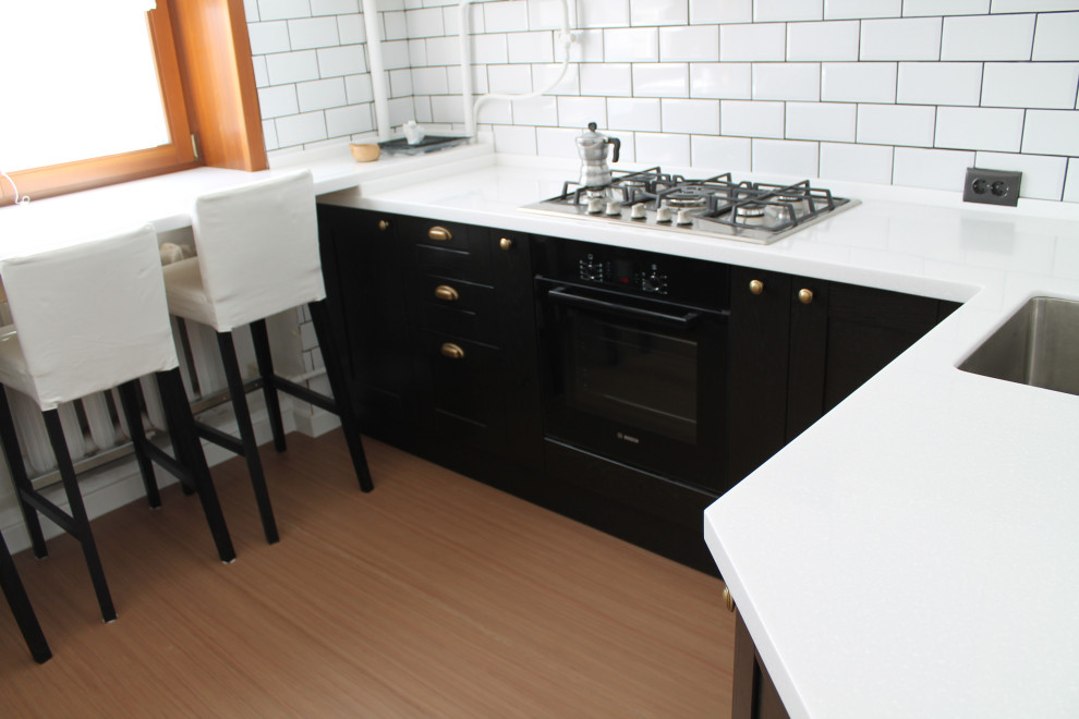 Inspiration för avskilda, små klassiska vitt u-kök, med en undermonterad diskho, luckor med upphöjd panel, bänkskiva i koppar, vitt stänkskydd, stänkskydd i tunnelbanekakel, svarta vitvaror, laminatgolv och brunt golv