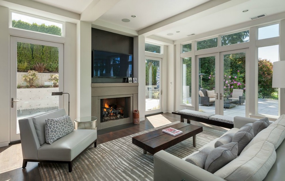 This is an example of a large transitional formal open concept living room in Seattle with grey walls, dark hardwood floors, a standard fireplace, a concrete fireplace surround and a wall-mounted tv.