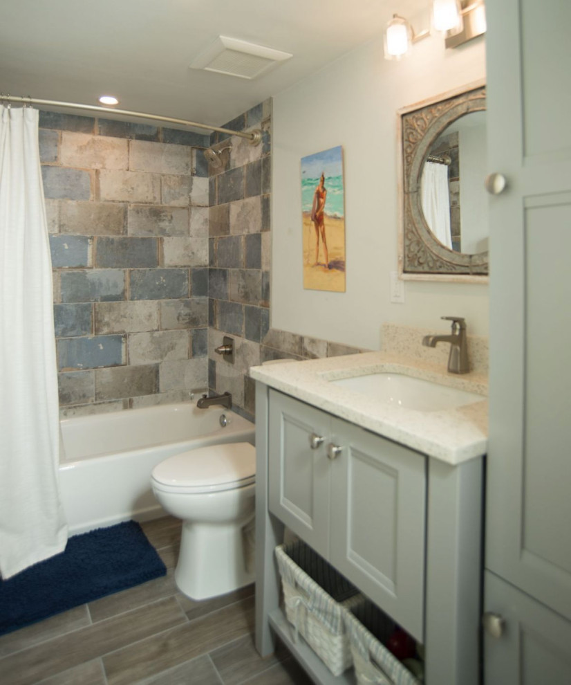 Photo of a small transitional kids bathroom in Orlando with recessed-panel cabinets, an alcove tub, a shower/bathtub combo, a one-piece toilet, stone tile, an undermount sink, recycled glass benchtops, grey floor, multi-coloured benchtops, a single vanity and a built-in vanity.