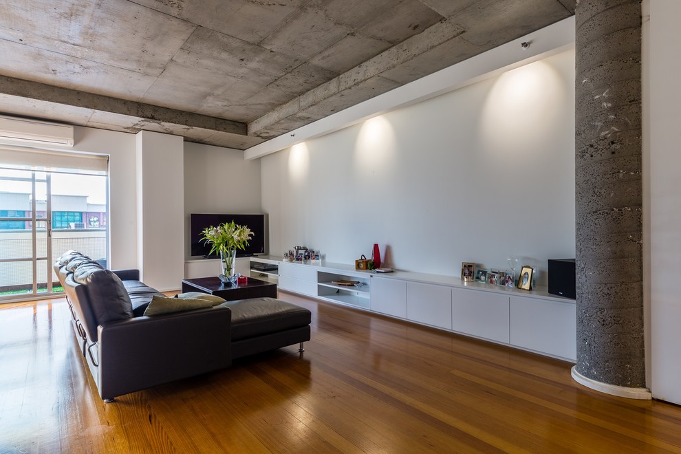 Design ideas for a mid-sized contemporary open concept living room in Melbourne with white walls, medium hardwood floors and a freestanding tv.
