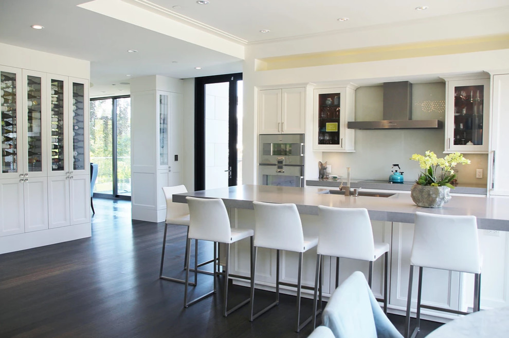 Mid-sized contemporary single-wall open plan kitchen in Vancouver with white cabinets, with island and brown floor.