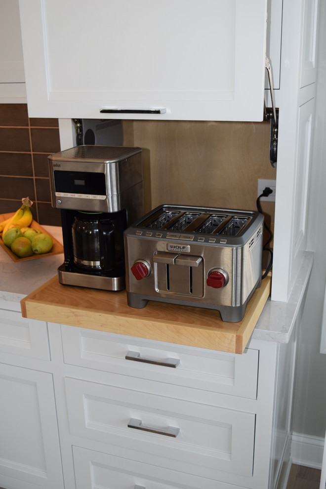 Inspiration for a large transitional l-shaped light wood floor and multicolored floor eat-in kitchen remodel in Chicago with beaded inset cabinets, white cabinets, quartz countertops, black backsplash, ceramic backsplash, stainless steel appliances and an island