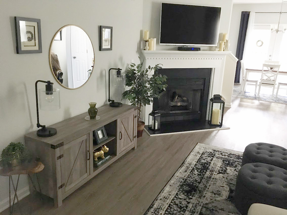 Inspiration for an arts and crafts living room in Raleigh with grey walls, laminate floors, a corner fireplace, a wood fireplace surround, a wall-mounted tv and grey floor.