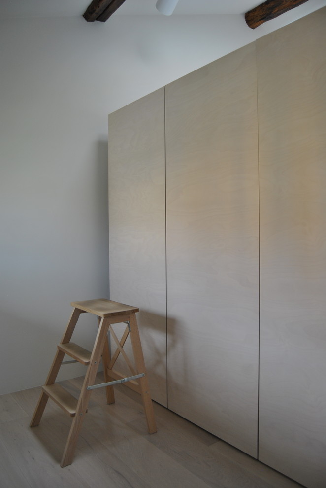This is an example of a small contemporary home studio in Milan with white walls, light hardwood floors, a freestanding desk and beige floor.