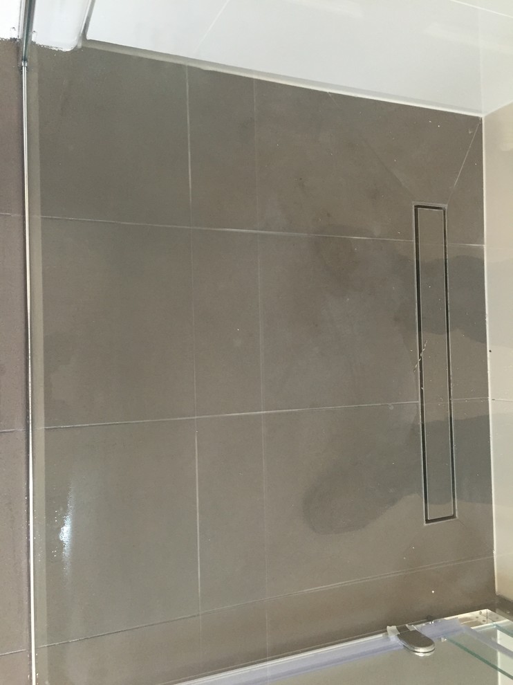 This is an example of a small modern master bathroom in Melbourne with raised-panel cabinets, white cabinets, a freestanding tub, a corner shower, a two-piece toilet, beige tile, porcelain tile, white walls, porcelain floors, an integrated sink and solid surface benchtops.