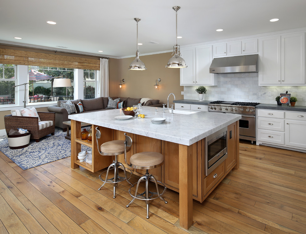 Traditional galley open plan kitchen in San Francisco with an undermount sink, shaker cabinets, white cabinets, white splashback, stainless steel appliances, medium hardwood floors, with island and marble benchtops.