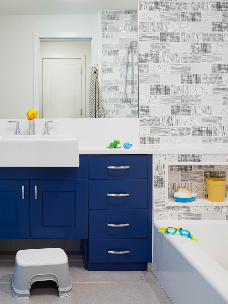 Inspiration for a mid-sized transitional kids bathroom in Seattle with blue cabinets, an alcove tub, a shower/bathtub combo, black and white tile, subway tile, multi-coloured walls, a drop-in sink, engineered quartz benchtops, grey floor, a shower curtain, white benchtops and shaker cabinets.