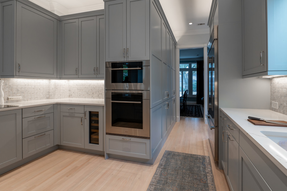 Inspiration for a large transitional u-shaped light wood floor and beige floor eat-in kitchen remodel in Houston with an undermount sink, shaker cabinets, gray cabinets, quartz countertops, ceramic backsplash, stainless steel appliances and white countertops