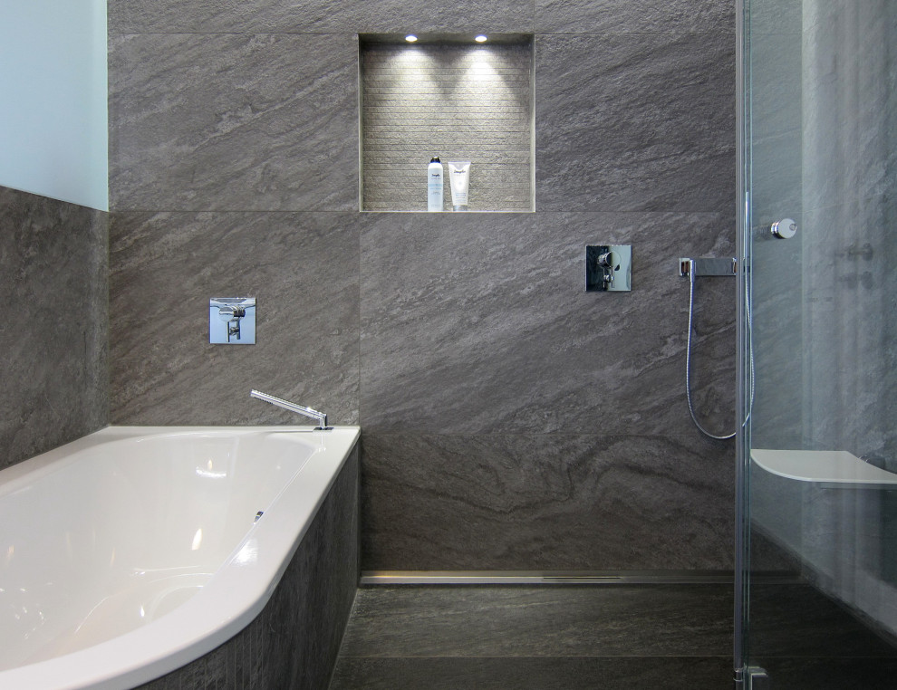 This is an example of a mid-sized contemporary bathroom in Bonn with a drop-in tub, a curbless shower, a wall-mount toilet, gray tile, ceramic tile, green walls, ceramic floors, solid surface benchtops, grey floor, a hinged shower door and white benchtops.