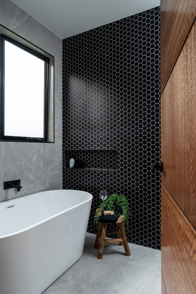 Design ideas for a mid-sized contemporary 3/4 bathroom in Adelaide with grey cabinets, a freestanding tub, black tile, mosaic tile, black walls, porcelain floors, engineered quartz benchtops, grey floor, white benchtops, a niche and a double vanity.