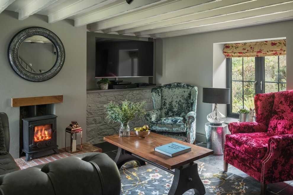 Esempio di un piccolo soggiorno tradizionale con pareti grigie, stufa a legna, TV a parete e pavimento nero