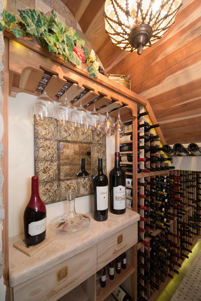 This is an example of a mid-sized mediterranean wine cellar in Phoenix with travertine floors and storage racks.