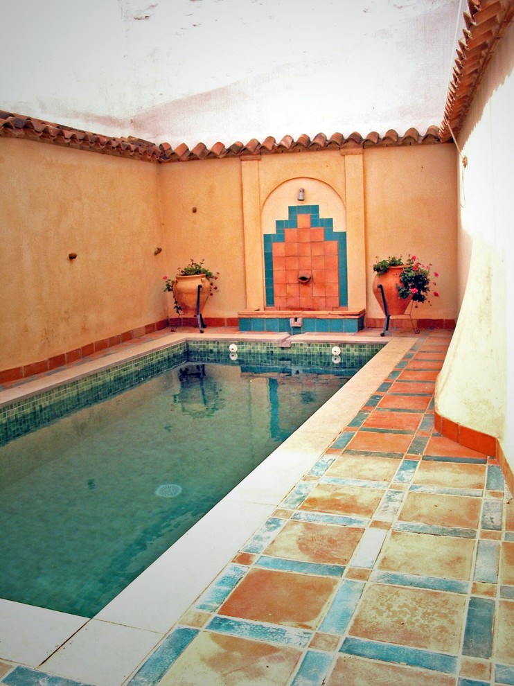 Small courtyard rectangular pool in Other with a water feature and tile.