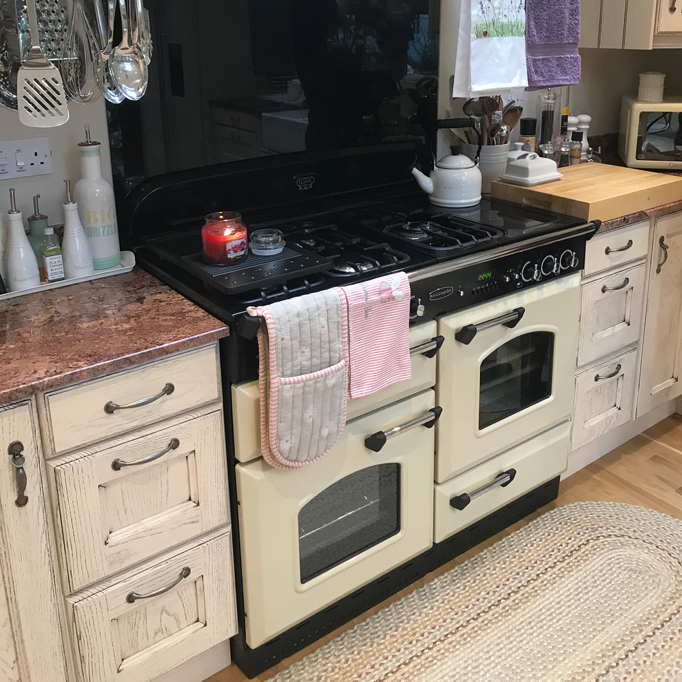 Photo of a mid-sized traditional l-shaped eat-in kitchen in Other with a farmhouse sink, raised-panel cabinets, distressed cabinets, granite benchtops and no island.