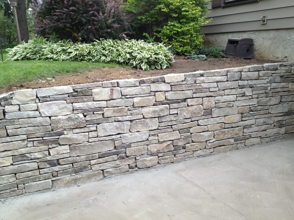 This is an example of a mid-sized country front yard garden in Minneapolis with a retaining wall and natural stone pavers.