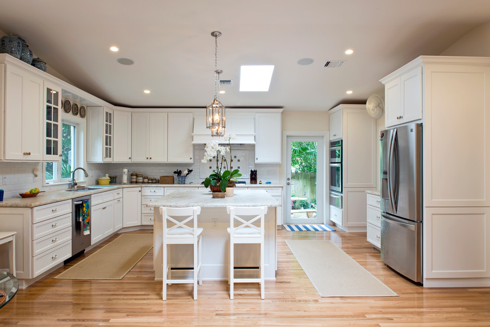Transitional l-shaped eat-in kitchen photo in Miami with white cabinets, white backsplash and stainless steel appliances