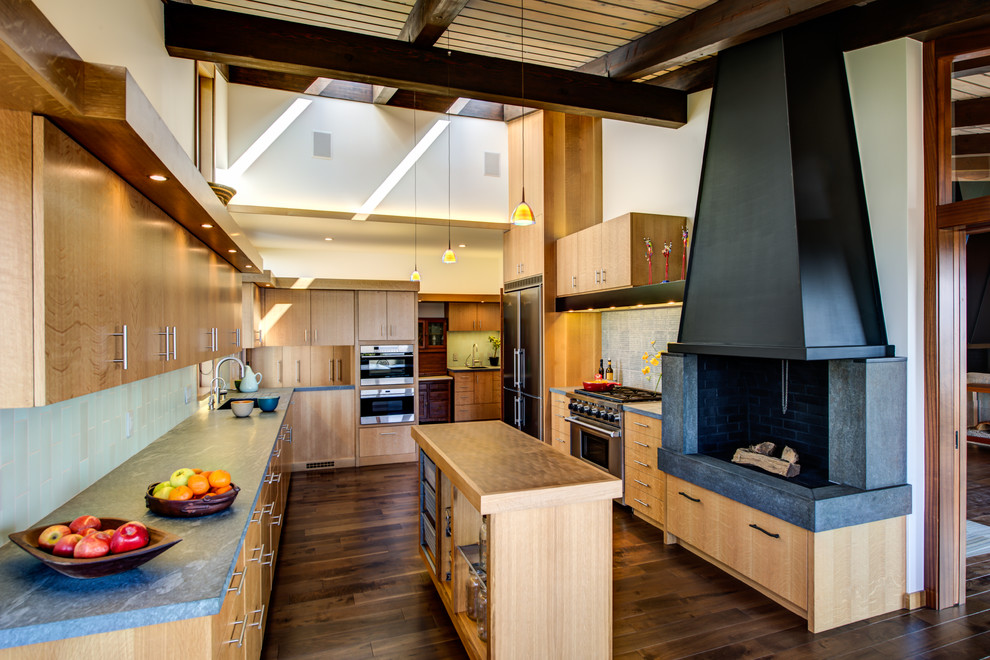 Large midcentury u-shaped eat-in kitchen in San Francisco with an undermount sink, flat-panel cabinets, light wood cabinets, soapstone benchtops, grey splashback, porcelain splashback, stainless steel appliances, dark hardwood floors, with island, brown floor and brown benchtop.
