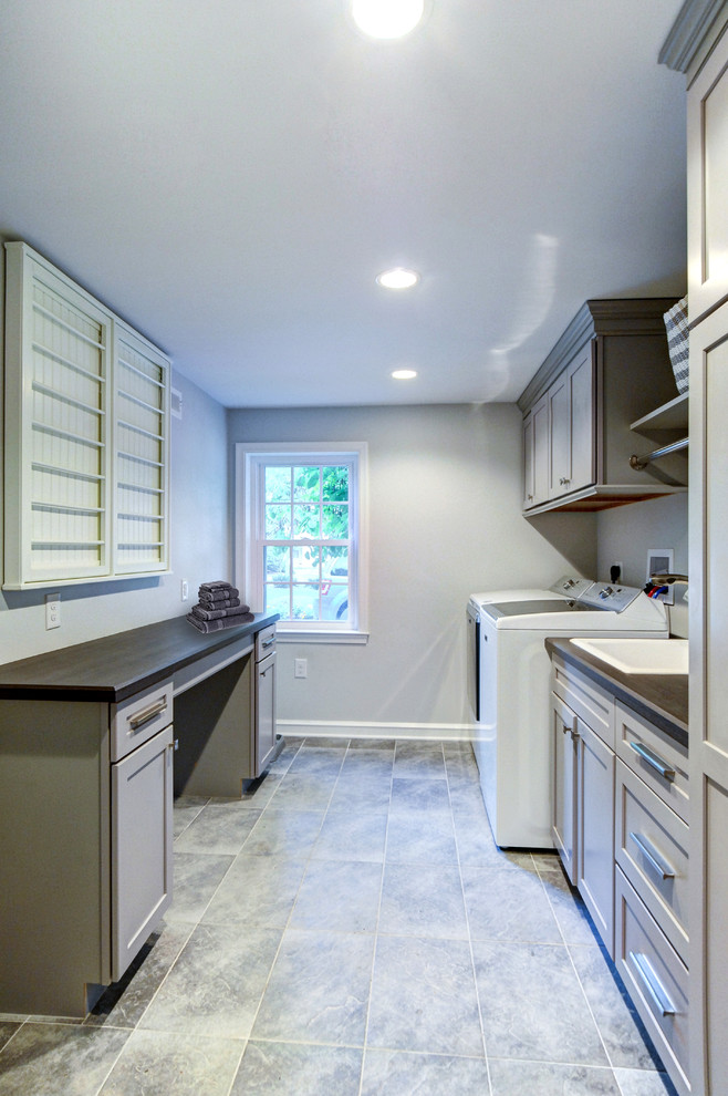 Transitional laundry room in Philadelphia with an utility sink, recessed-panel cabinets, grey cabinets, laminate benchtops, grey walls, porcelain floors, a side-by-side washer and dryer, grey floor and brown benchtop.