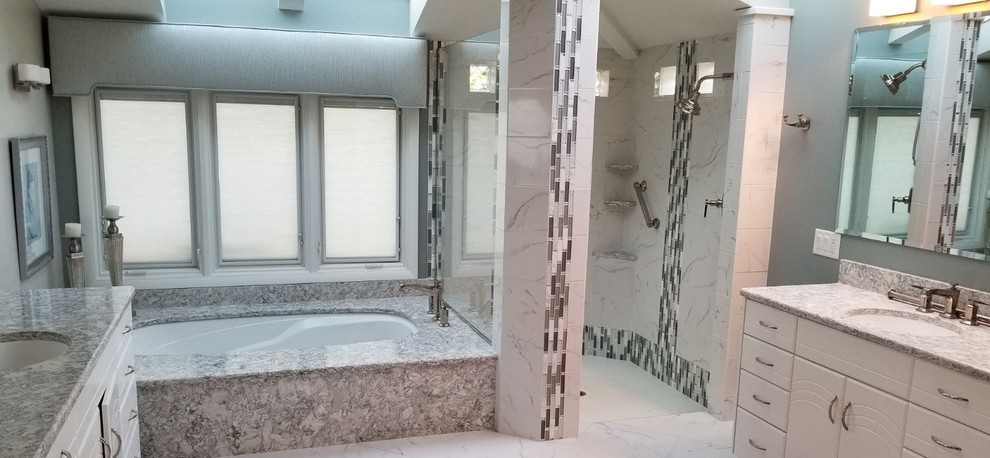Large transitional master white tile and porcelain tile porcelain tile and white floor doorless shower photo with flat-panel cabinets, white cabinets, an undermount tub, gray walls, an undermount sink, solid surface countertops and gray countertops