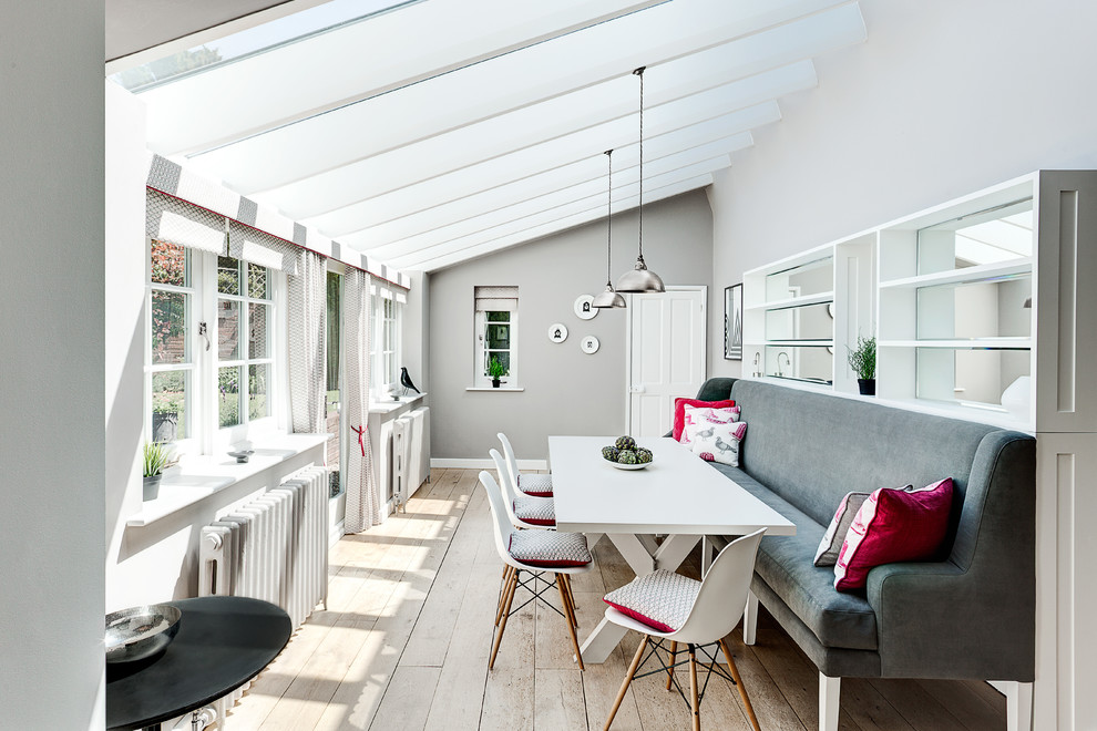 Photo of a contemporary dining room in London with grey walls and medium hardwood floors.
