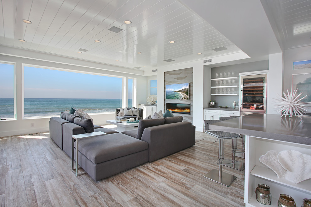 Beach style living room in Orange County with white walls, a ribbon fireplace and a wall-mounted tv.