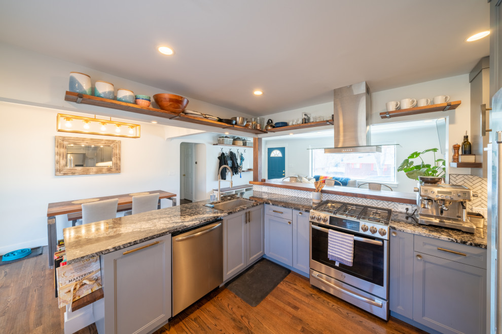 Inredning av ett modernt mellanstort flerfärgad flerfärgat kök, med en undermonterad diskho, skåp i shakerstil, blå skåp, granitbänkskiva, vitt stänkskydd, stänkskydd i keramik, rostfria vitvaror, mörkt trägolv och brunt golv