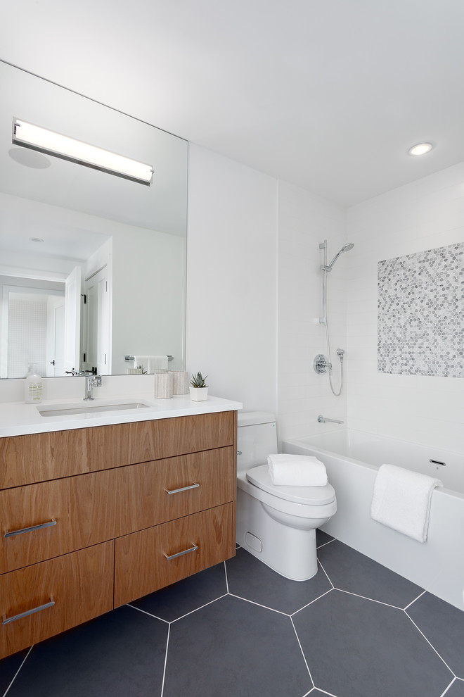 Photo of a mid-sized transitional kids bathroom in Vancouver with flat-panel cabinets, brown cabinets, a shower/bathtub combo, a two-piece toilet, white tile, mosaic tile, white walls, porcelain floors, an undermount sink, engineered quartz benchtops, grey floor, a shower curtain and white benchtops.