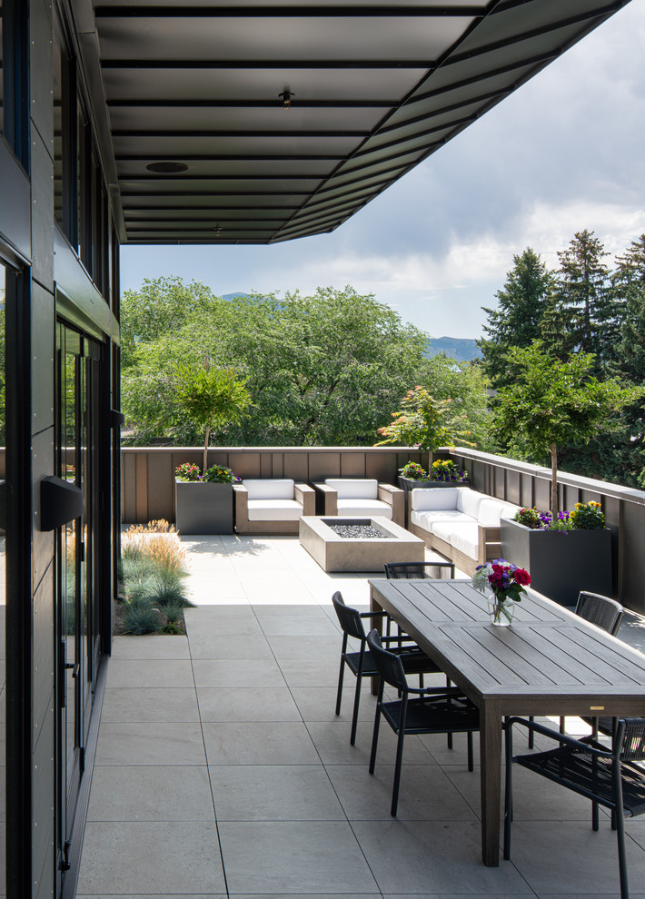 Photo of an expansive transitional rooftop deck in Boise with a fire feature and a roof extension.