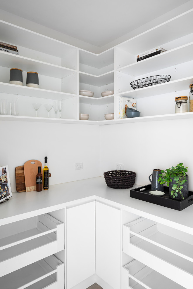 Photo of a mid-sized modern galley open plan kitchen in Melbourne with an undermount sink, flat-panel cabinets, white cabinets, quartz benchtops, white splashback, glass sheet splashback, stainless steel appliances, concrete floors, with island, grey floor and white benchtop.