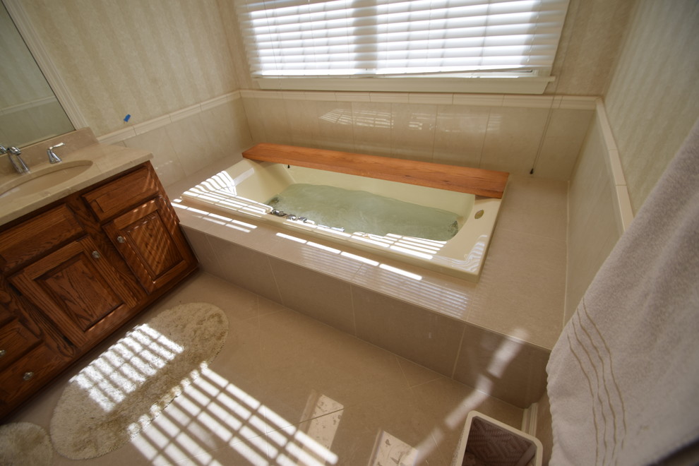 Drop-in bathtub - mid-sized transitional master beige tile and porcelain tile porcelain tile and gray floor drop-in bathtub idea with raised-panel cabinets, medium tone wood cabinets, a one-piece toilet, blue walls, an undermount sink, marble countertops and multicolored countertops